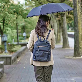 画像：女性が日傘を差してリュックを背負っている後ろ姿