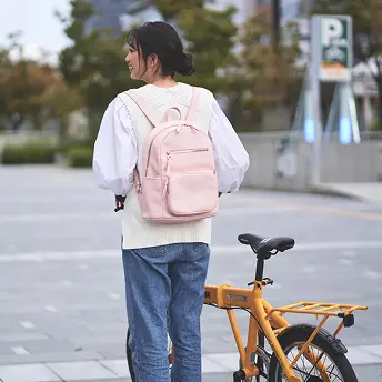 画像：女性がリュックを背負いながら自転車をひいている様子